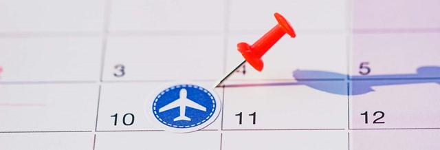 Kalender met rode pinmarker en vliegtuigsymbool