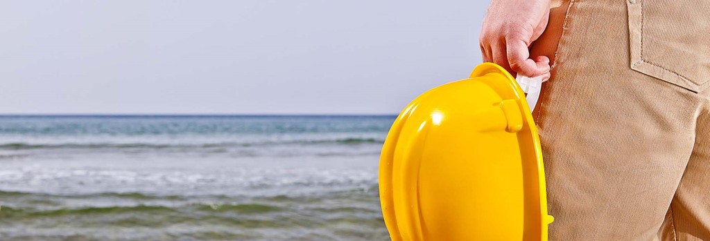 Man met gele helm op strand