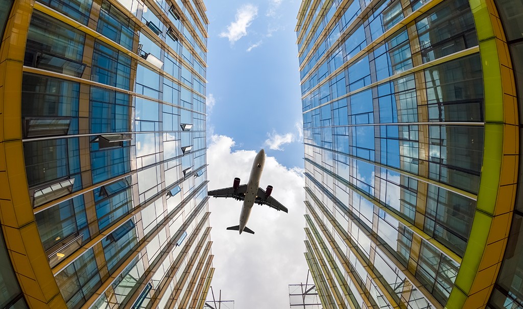 Vliegtuig over gebouw met glas - geluidsisolerende beglazing - OnderhoudNL en Bouwend Nederland